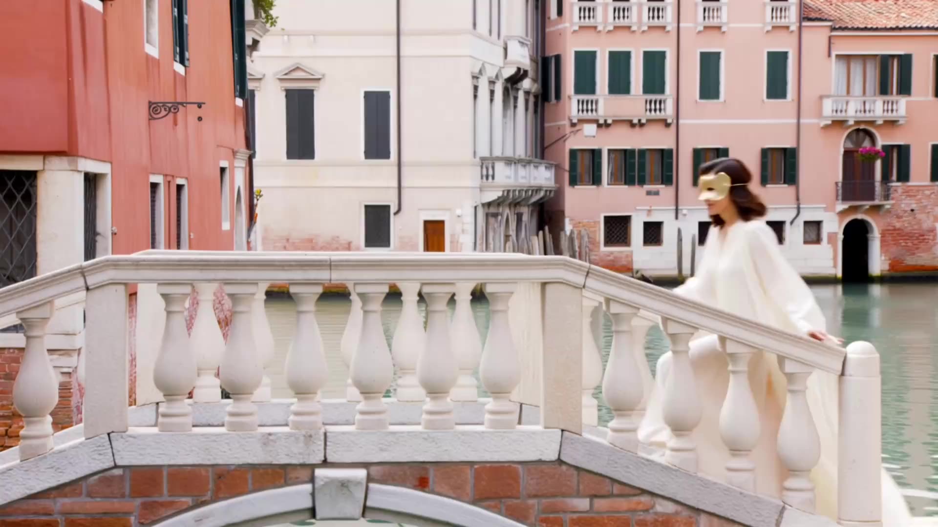 Frau in heller Robe mit goldener Maske auf einer Steinbrücke in Venedig, Fachbereich Ästhetik