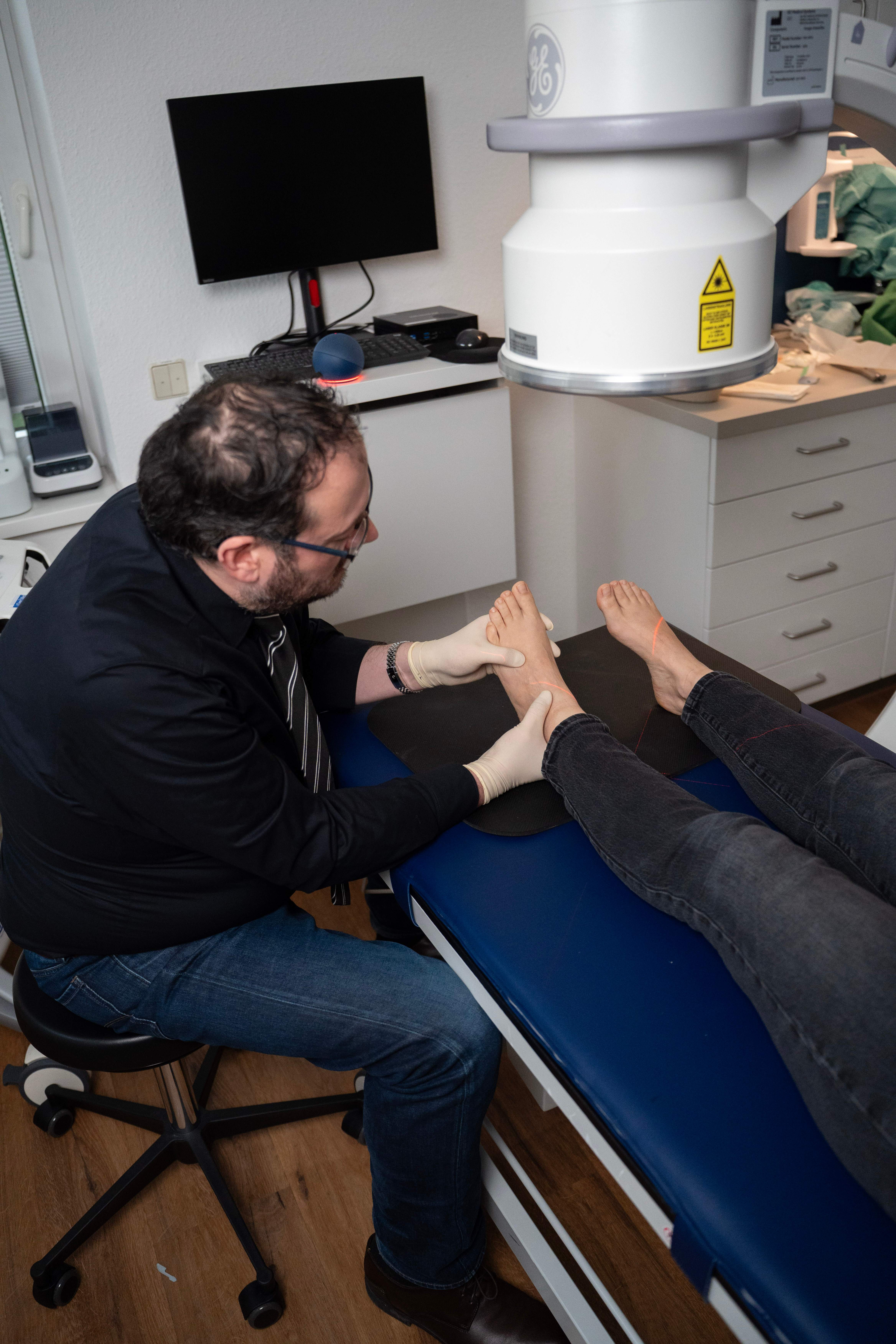 Dr. Velickovic untersucht den Fuß einer Patientin unter dem Röntgengerät